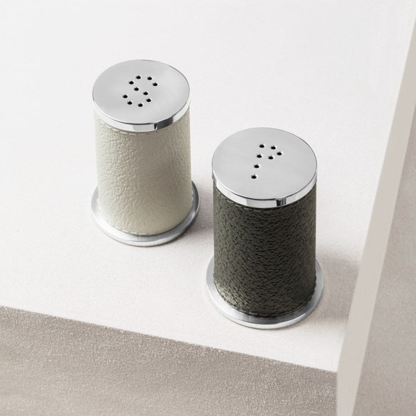  Salt and Pepper Shakers Set Otello by Giobagnara in leather and stainless steel with textured bodies and metallic tops on a light background