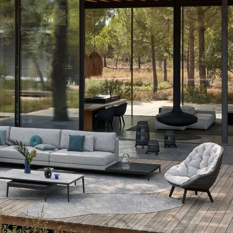 Modern outdoor living space with gray sofa, white chair, and wooden deck.