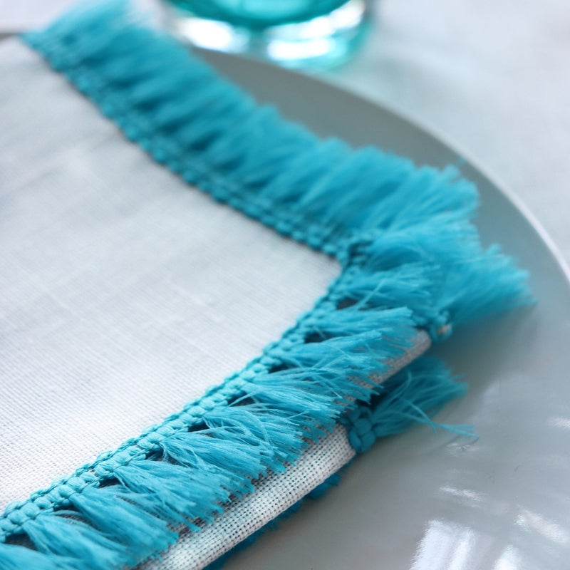 Close-up of a turquoise fringed napkin on a white plate
