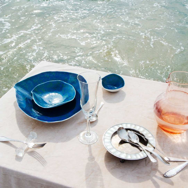 Table setting with Ocean-inspired porcelain large dinner plates Blue Lagoon No6 Indulge Sarah-Linda and silverware by the water