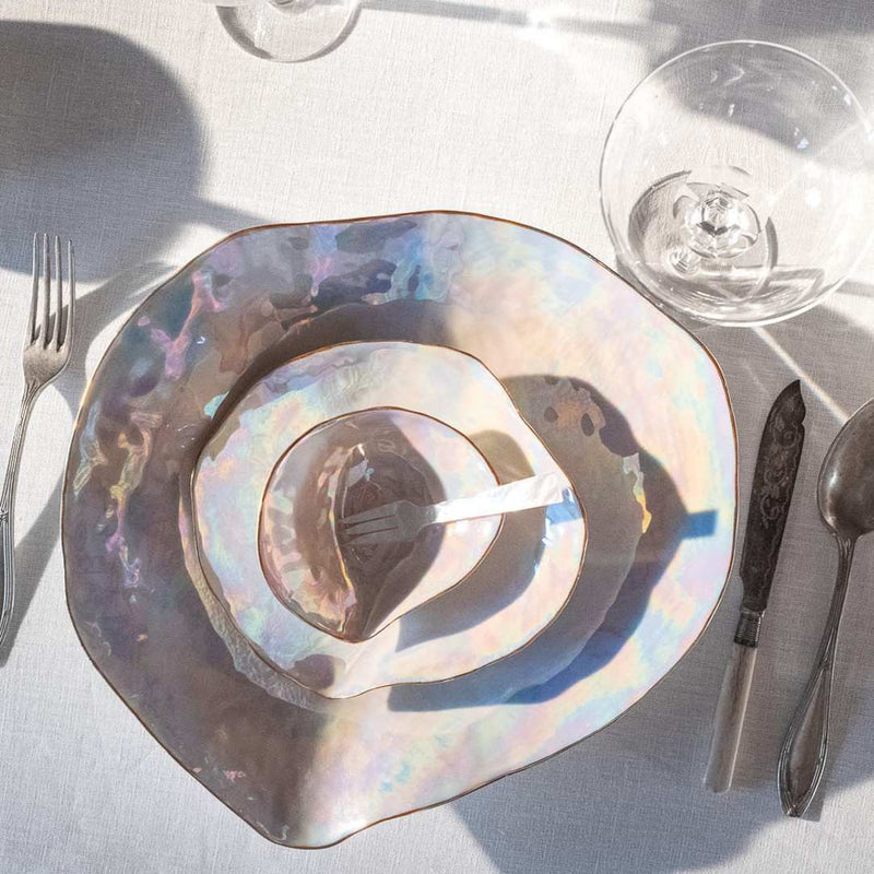Shell-inspired porcelain side bowls pearlescent finish Nº2 Indulge Sarah-Linda on a table setting with cutlery and a glass.