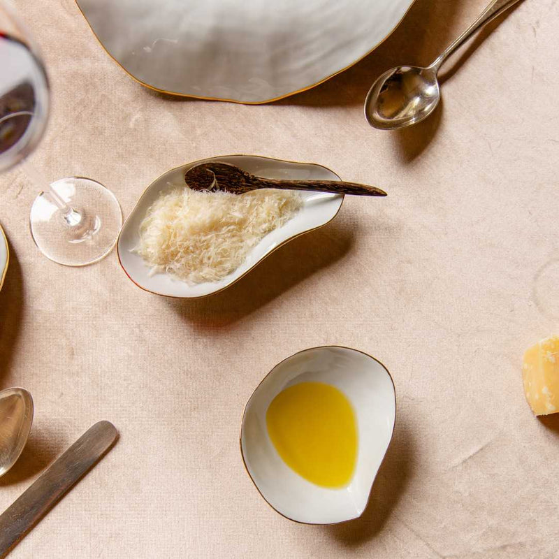 Sculptural porcelain side bowls white with gold edge Nº2 Indulge on a beige surface with utensils.