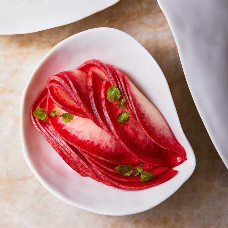 Sliced red fruit on a Shell-inspired porcelain side bowls White No2 Indulge Sarah-Linda with a marble background