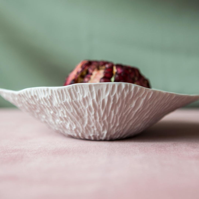 Sculptural porcelain small deep plates White No9 Indulge Sarah-Linda on a pink surface with a blurred background