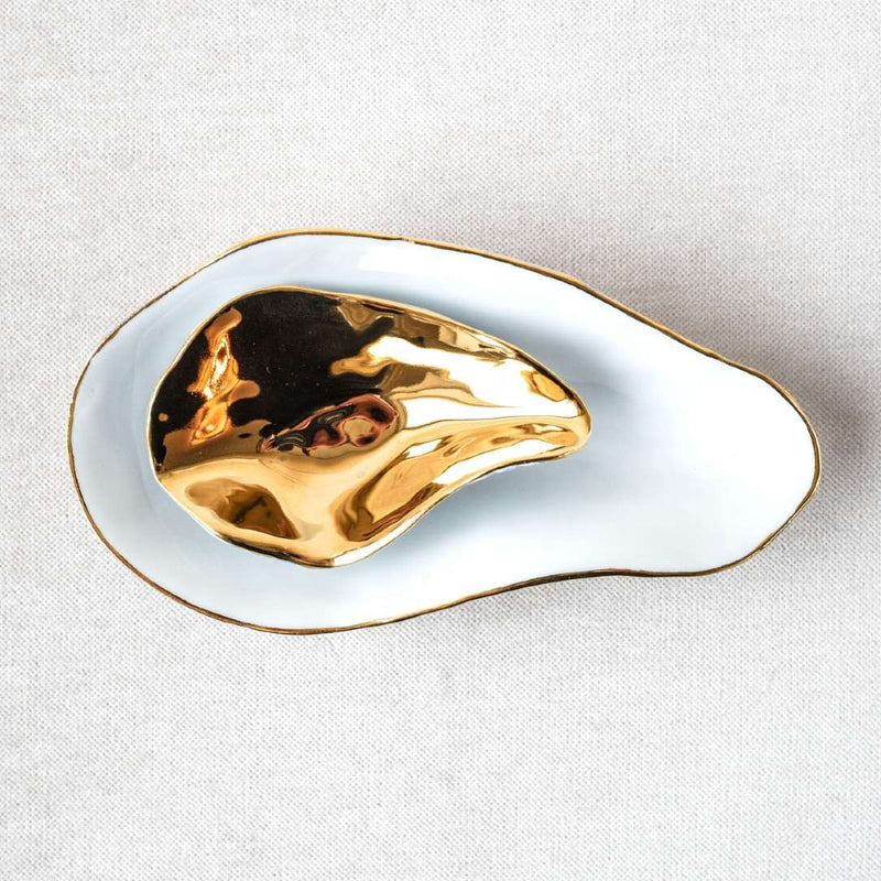 Shell-inspired porcelain gold spoons Nº1 Indulge Sarah-Linda on a white plate against a light gray background