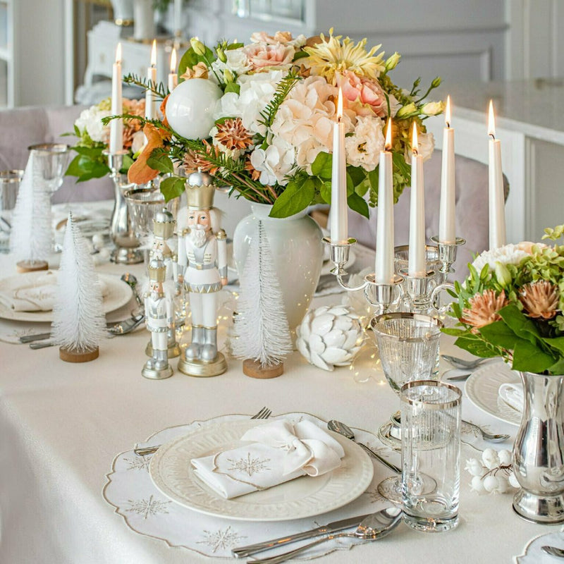 Elegant table setting with a shiny silver tablecloth, white plates, and decorative candle holders with a festive atmosphere.