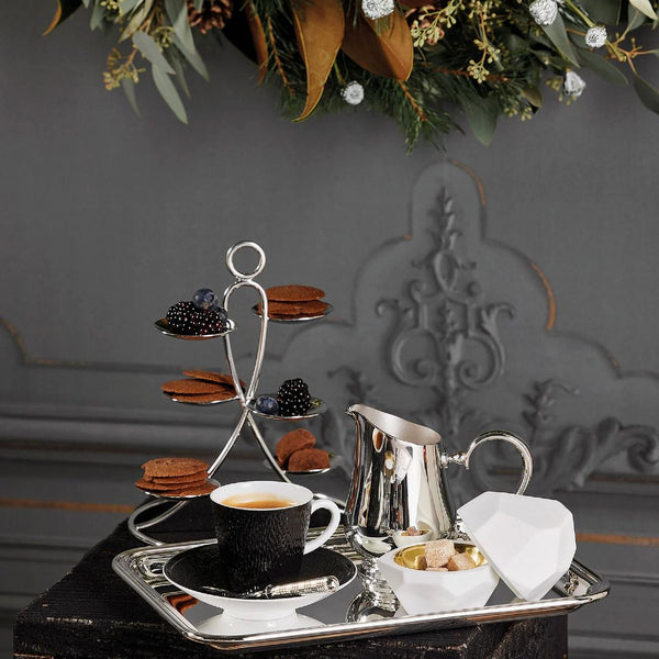 Tea set with cup, Rencontre milk jug 30cl and cookies on a tray against a decorative wall.