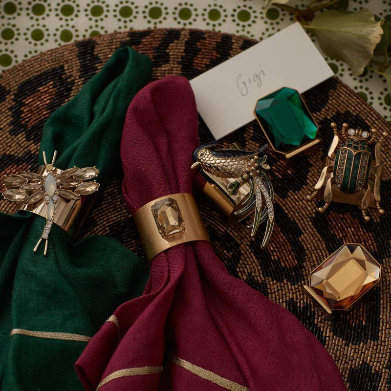 Decorative napkin rings with green and gold colors on a patterned surface.