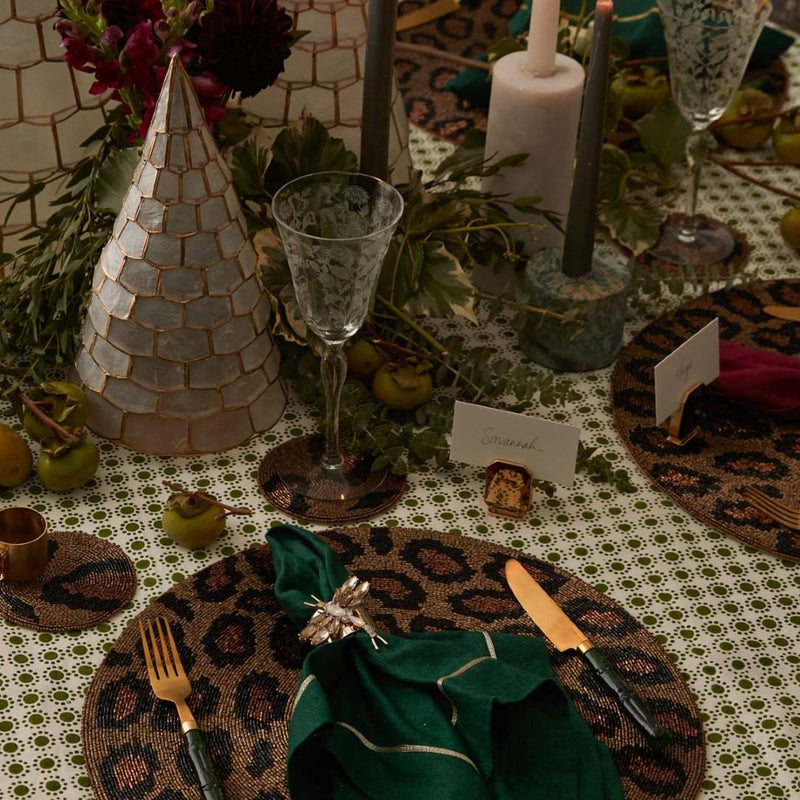 Decorative table setting with leopard print placemats, green napkins, and Single Gem place card holder in topaz-colored glass and gold finish by Joanna Buchanan