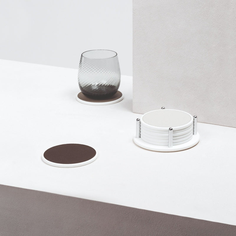 Glass with a textured design on a white surface, accompanied by coasters.