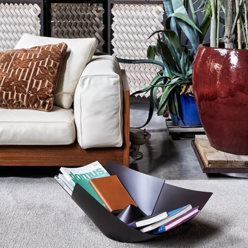 Decorative black bowl with magazines on a gray rug in a living room setting.
