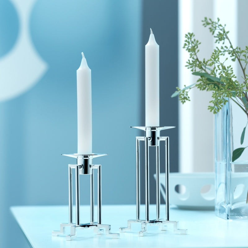 Styled Sphinx candle holders short and tall with white candles on a light blue background