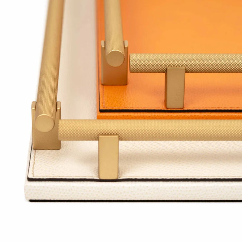 Close-up of the Robert tray knurled brass bars with an orange interior on a white background