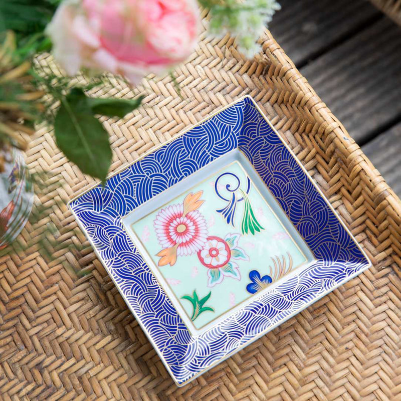 Decorative ceramic plate with floral design on a woven surface
