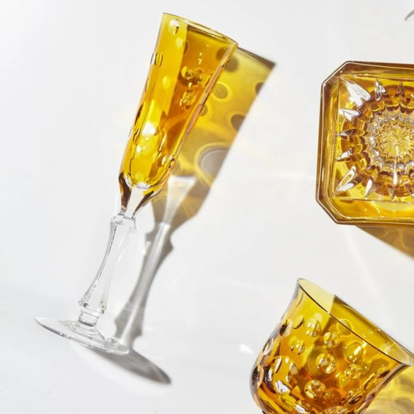 Amber Staccato champagne flute with bubble cut crystal design by Cristallerie de Montbronn on a white background