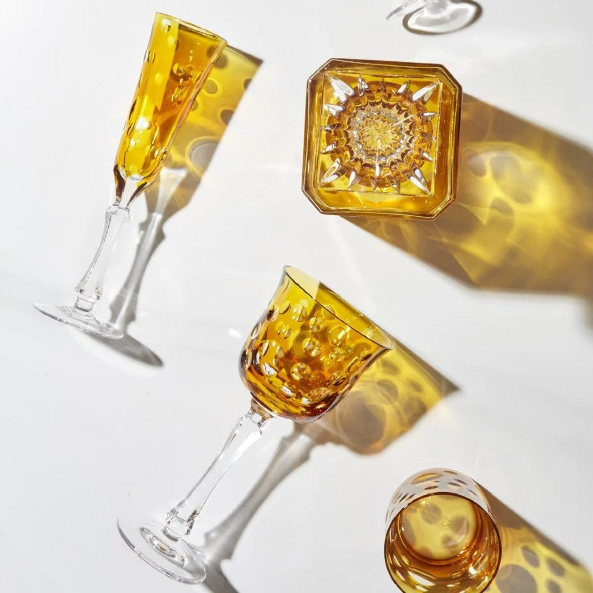 Staccato by Cristallerie de Montbronn, crystal glassware in amber with bold bubble cuts and modern geometry, inspired by musical rhythm. on a white background