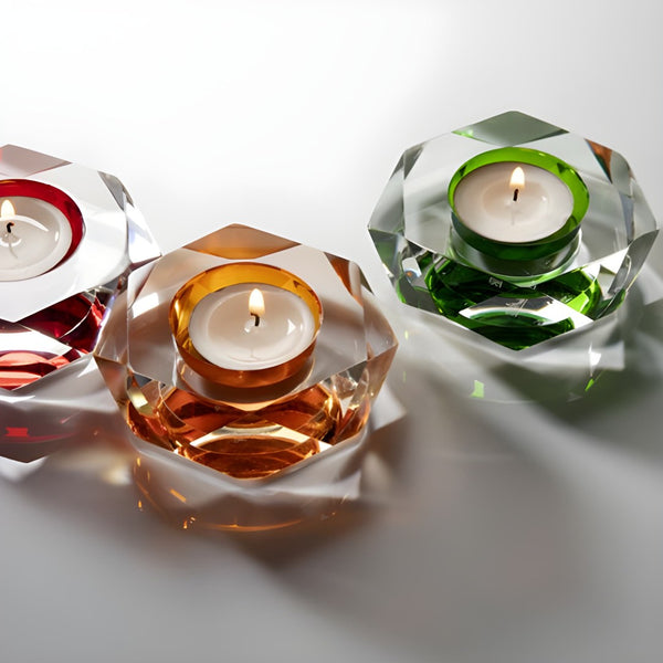 Three crystal candle holders with lit candles on a white background