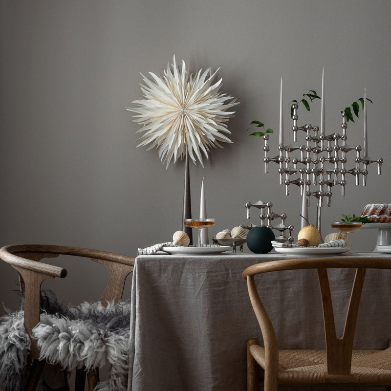 Dining room with a table set for a meal, featuring a decorative wall piece and candlesticks.