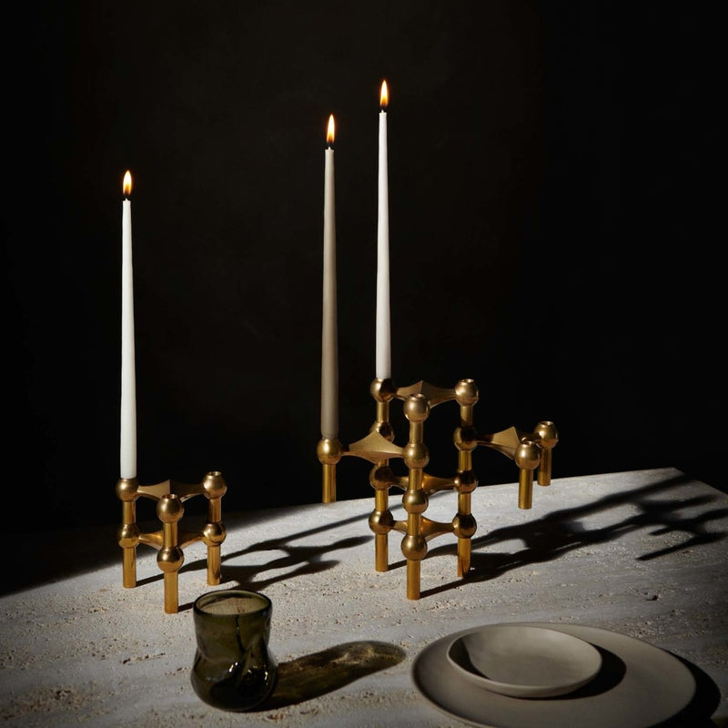 Stoff Nagel candle holders in brass with patina vintage look with lit candles on a dark background