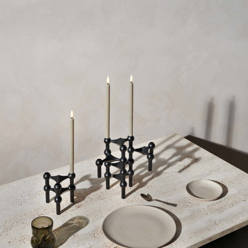 Black candle holder with candles on a stone surface