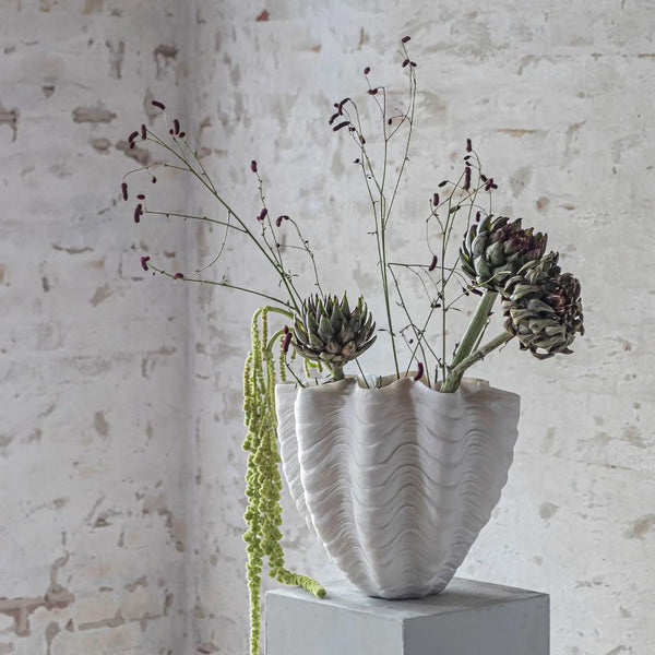 White textured vase with plants on a light stone background