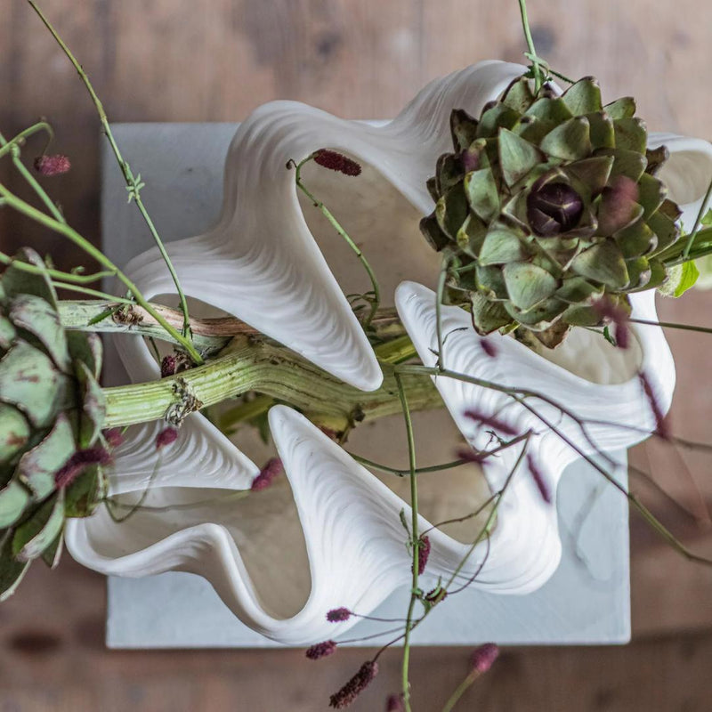 Artichoke with a white ceramic sculpture on a wooden surface