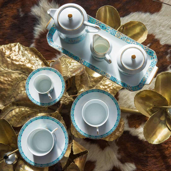 Tea set with teapot, cups, and saucers on a decorative tray with gold leaves.