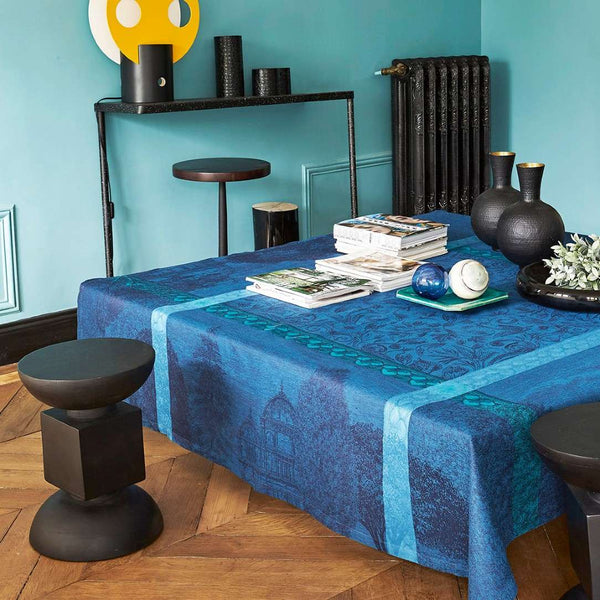 Blue patterned tablecloth on a table with decorative items against a teal wall.
