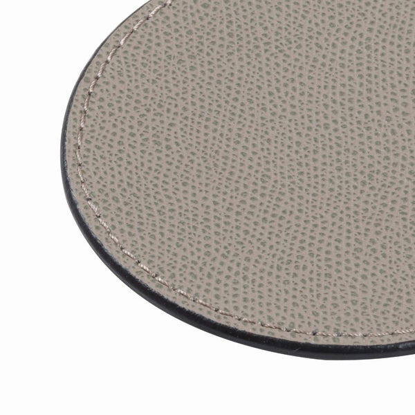 Close-up of a textured gray leather coaster on a white background