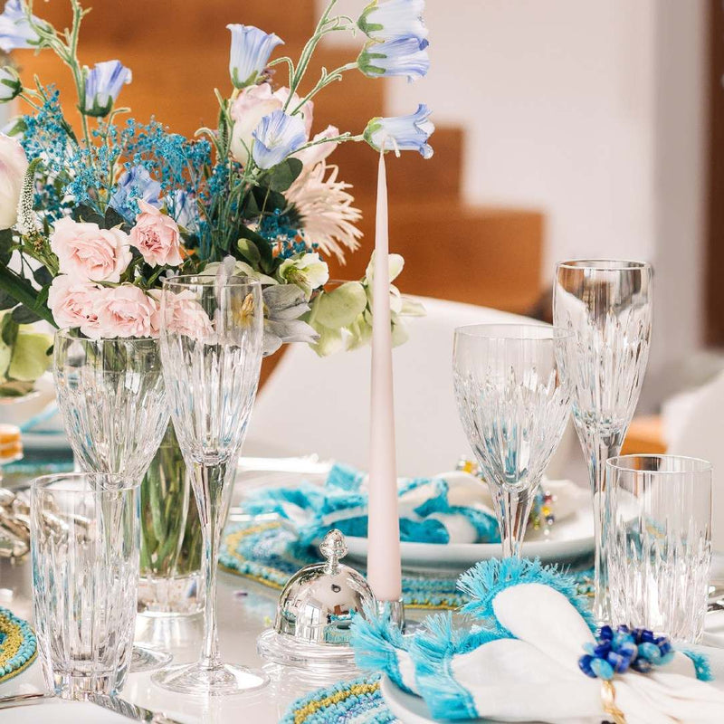 Decorative table setting with flowers, glasses, and a candle on a blurred background