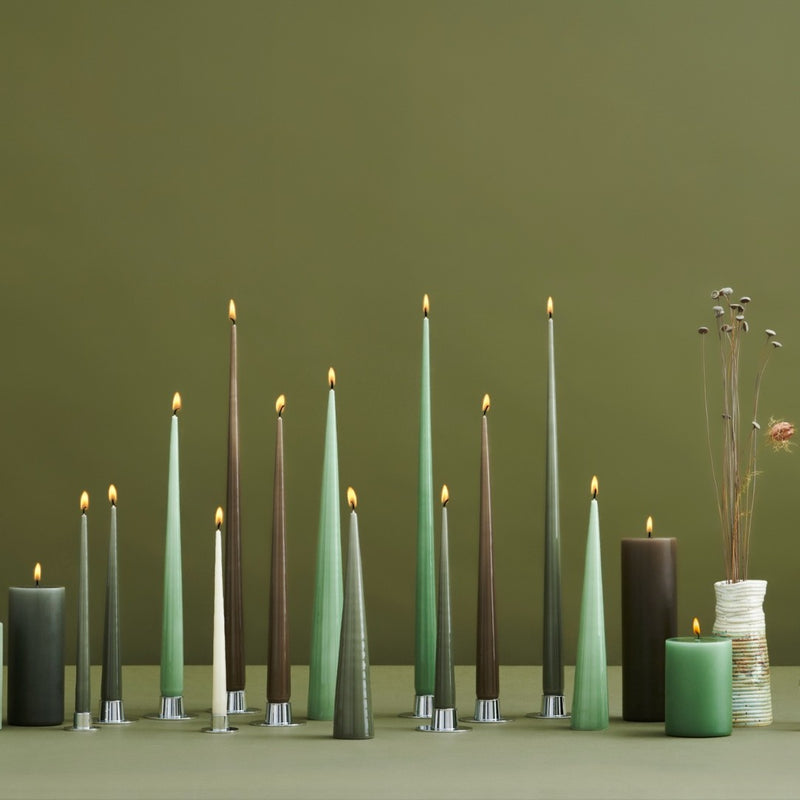 Row of green and brown candles with a vase of dried flowers on a green background