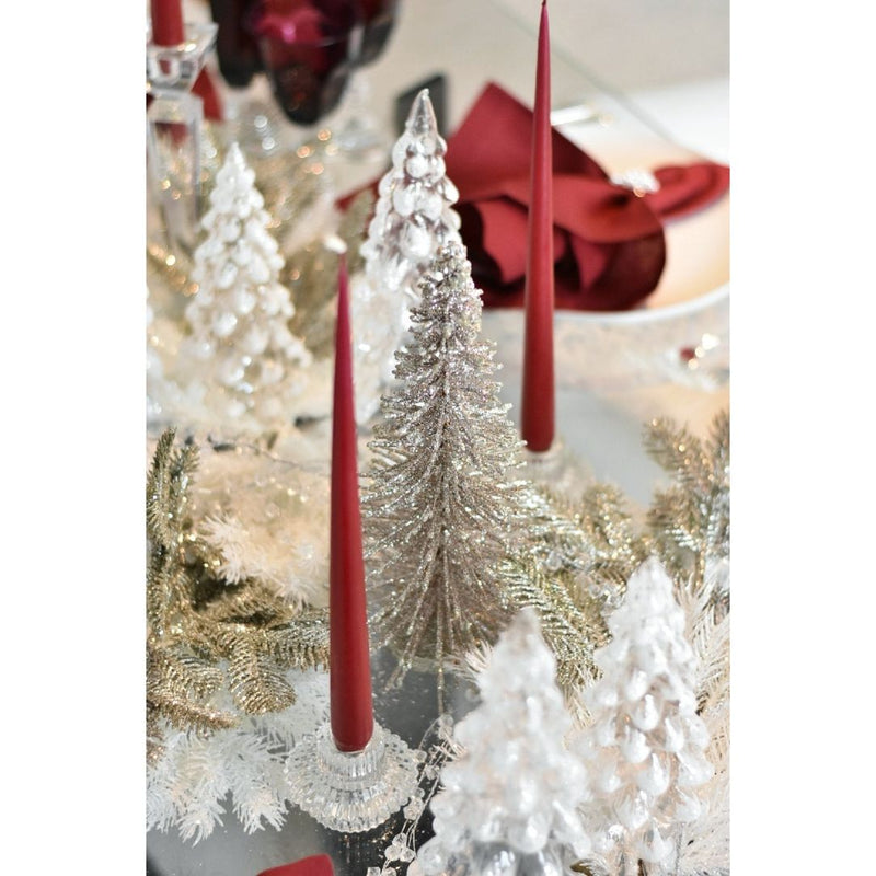 Decorative table setting with red candles, silver trees, and gold tinsel.