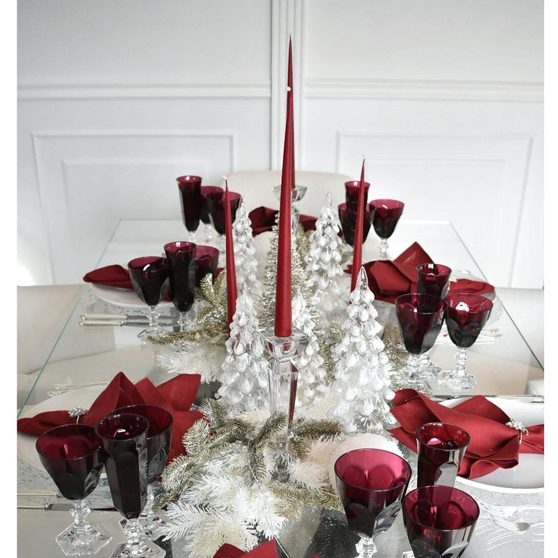 Decorative table setting with red candles, glasses, and napkins on a white background