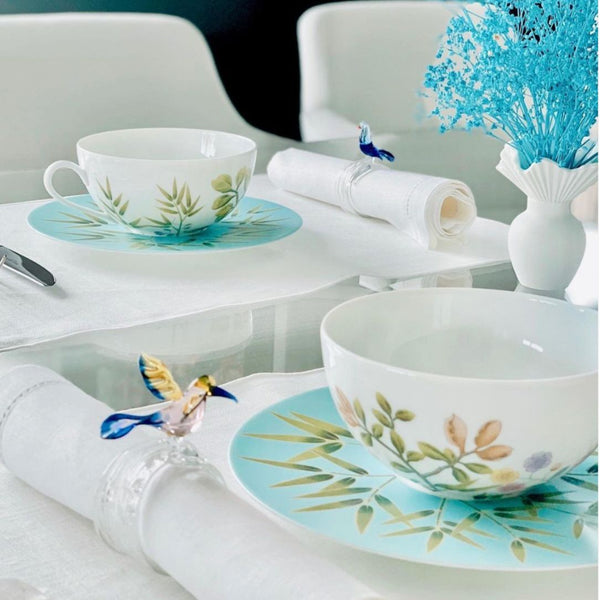 Table setting with floral teacups and plates on a white table.