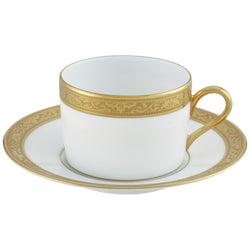 A white porcelain tea cup with gold Renaissance style border inlaid with fine gold details, accompanied by a saucer with a matching design.