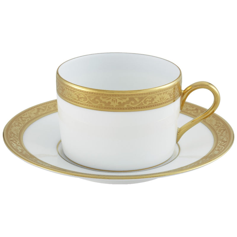 A white porcelain tea cup with gold Renaissance style border inlaid with fine gold details, accompanied by a saucer with a matching design.