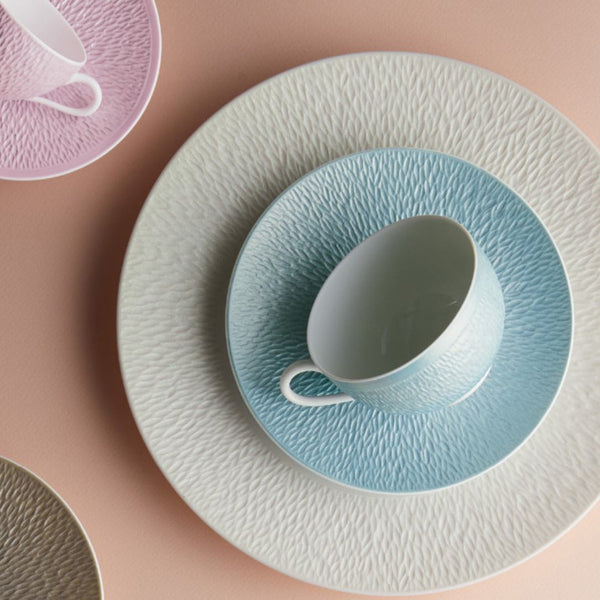 Teacup and saucer set with textured design on a pink background