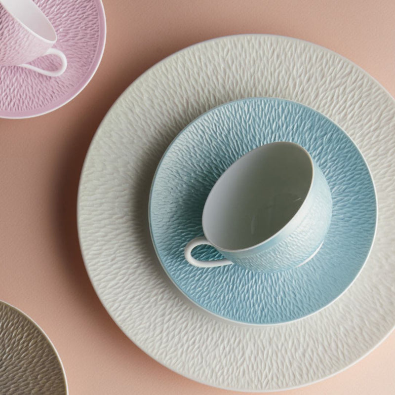 Teacup and saucer set with textured design on a pink background