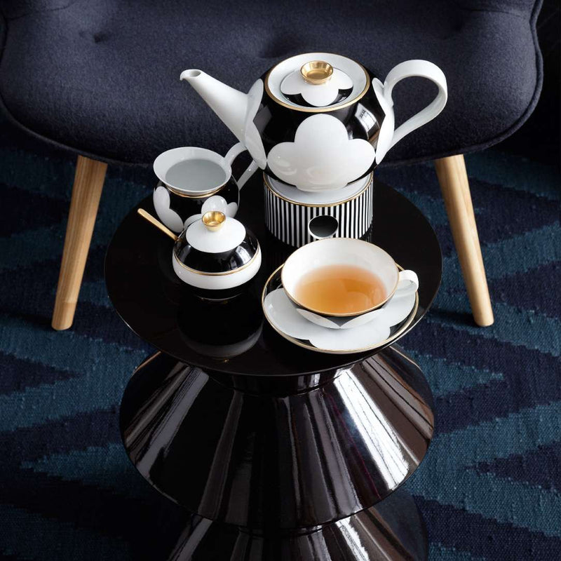 Tea set featuring 0.6l teapot on a black round table with a dark blue striped rug in the background