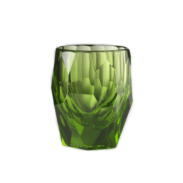 Green glass tumbler with textured surface on a white background