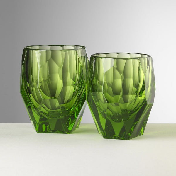 Two green faceted glass tumblers on a light gray background