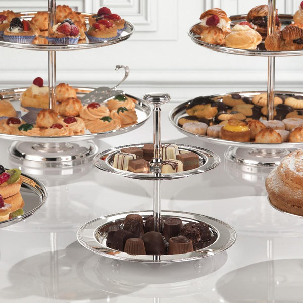 Three-tiered silver dessert stand with various pastries on a white surface
