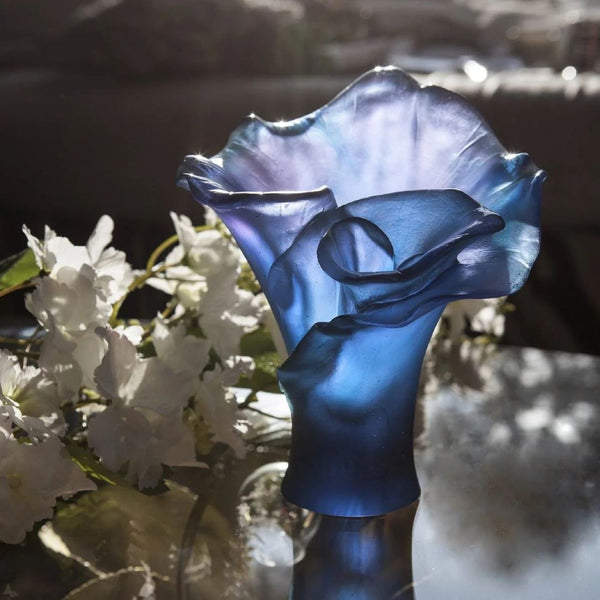 Blue glass vase Arum with white flowers in the background