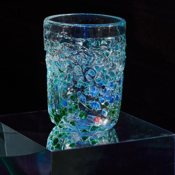 Glass vase with textured surface on a reflective black surface
