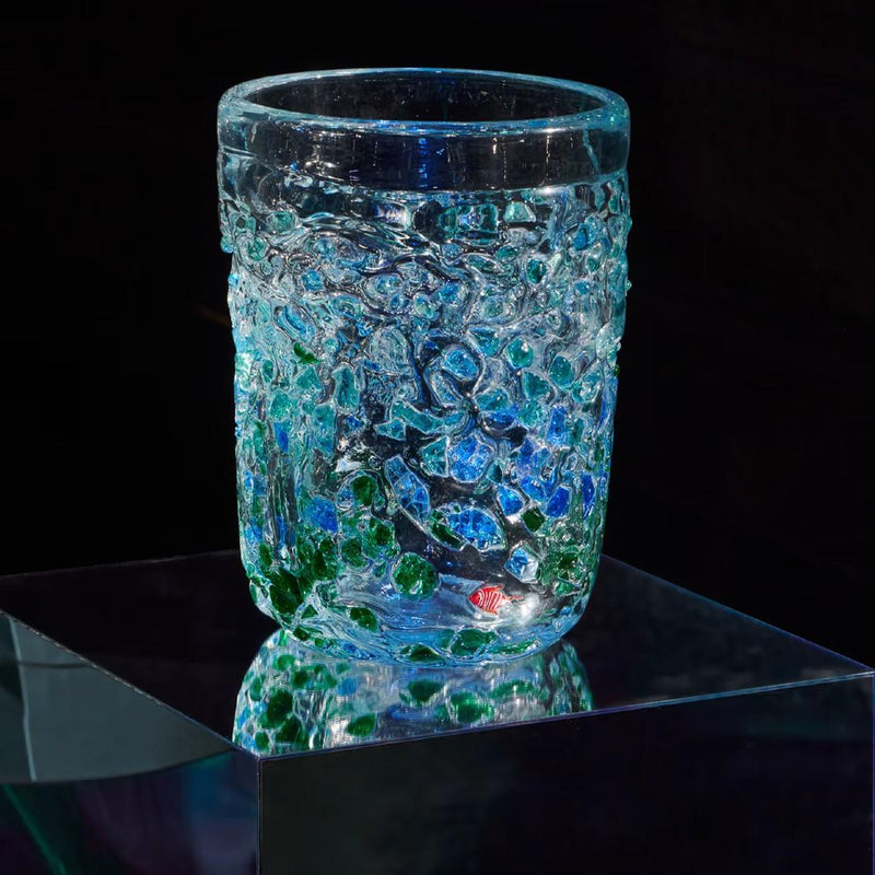 Glass vase with textured surface on a reflective black surface