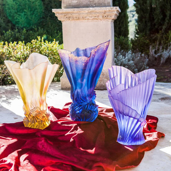 Three colorful glass vases on a red cloth with a garden background