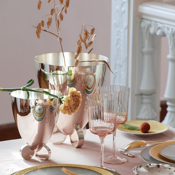 Decorative table setting with glasses, plates, and flowers on a white surface.