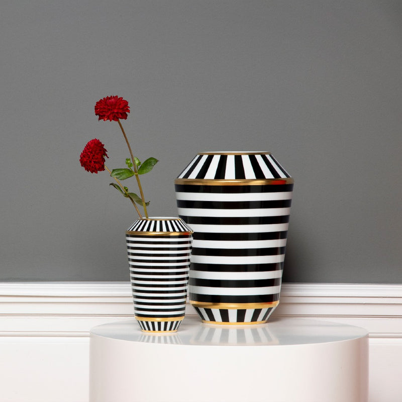 Two black and white striped vases with gold accents on a gray background