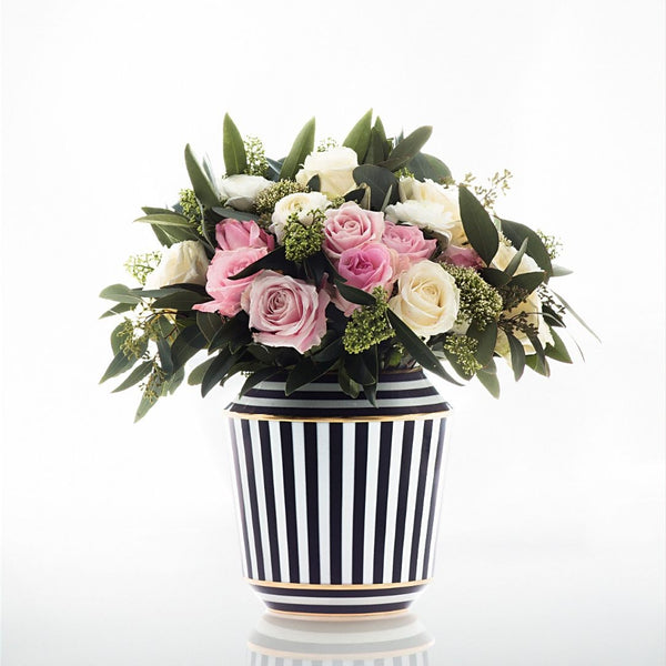 Floral arrangement in a black and white striped vase on a white background