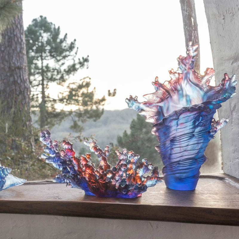 Two colorful glass sculpture vases on a windowsill with a natural outdoor background